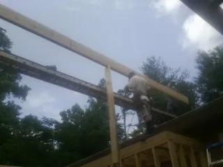 Carpenter setting a ridge beam over a new addition frame — Ice Dam Removal by Roofing Brothers in Saint John