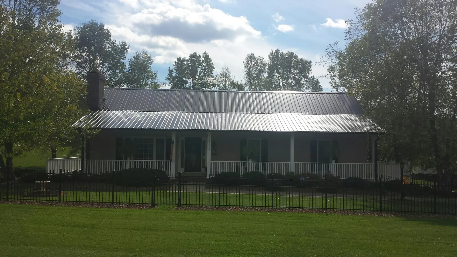 Gray metal roof on a brick ranch with a full width front porch — Gutter Guard Installation work by our crew in Saint John