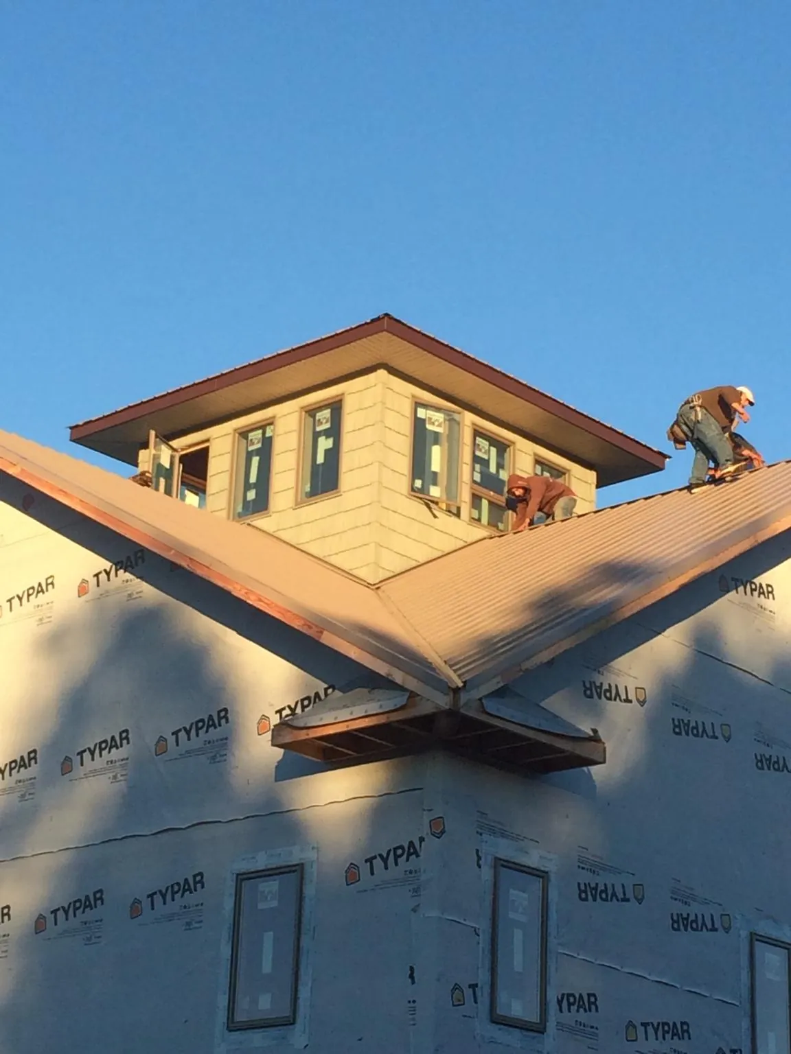 Roofers working around a rooftop cupola on a new metal roof at sunset — Roof Waterproofing in Saint John by Roofing Brothers